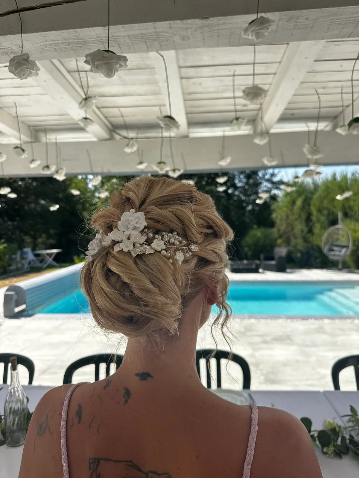 Chignon bas tressé avec accessoire floral réalisé par Coleen pour un mariage