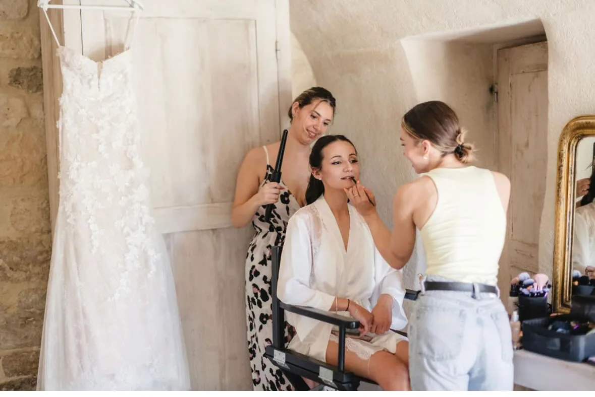 Mariée assise devant sa robe pendant les derniers préparatifs de coiffure